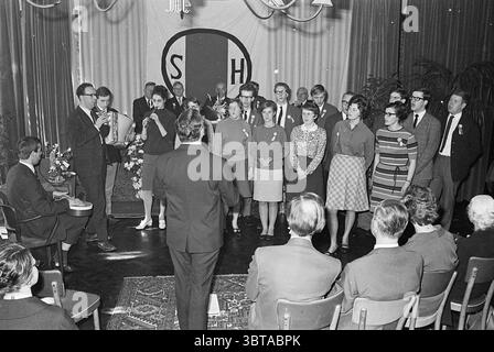 50° anniversario di Ned. Lontano. Kit per non udenti Haarlem Jubilee Anniversaries, Whizgle News, Dutch Desk, Paesi Bassi, 1950 - 2000 il 01-04-1967. Questi sono gli argomenti nell'immagine. In un ambiente interno scarsamente illuminato, un gruppo di persone si erge in un semicerchio, formando un coro. La scena è vivace e coinvolgente, catturando un senso di comunità e gioia. Gli individui sono vestiti con abiti che riflettono varie sfumature degli anni '1960, con alcuni che indossano colori brillanti come il rosso e l'ottanio, mentre altri sono vestiti con toni più tenui e terrosi. Ogni persona sembra indossare un'etichetta con il nome, aggiungendo una t personale Foto Stock