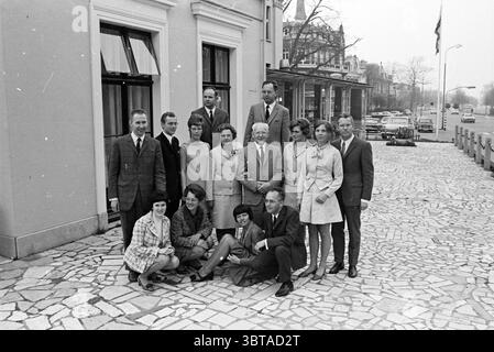 Foto di gruppo delle famiglie Piet, Whizgle News, Dutch Desk, Paesi Bassi, 1950 - 2000 il 02-05-1969. Questi argomenti sono mostrati nell'immagine. La scena cattura un gruppo di persone poste fuori da un elegante edificio con uno stile architettonico tipico del design europeo della metà del XX secolo. L'esterno presenta pareti in pietra di colore chiaro e grandi finestre che riflettono un senso di sofisticazione. In primo piano, un gruppo eterogeneo di quattordici individui si trova disposto su due file. La prima fila è composta da un mix di uomini e donne. Le donne sono vestite con una varietà di abiti alla moda, con S Foto Stock