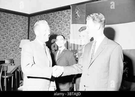 T.H.B. 0 Years Recetions, Whizgle News, Dutch Desk, Paesi Bassi, 1950 - 2000 il 23-05-1964. L'immagine include questi argomenti. In un ambiente interno ben illuminato, un gruppo di quattro uomini è impegnato in un momento di interazione e cameratismo. La camera presenta carta da parati testurizzata ornata da un motivo floreale che aggiunge un tocco di calore alla scena. Due uomini sono ben posizionati in primo piano, condividendo una stretta di mano. Un gentiluomo, con i capelli argentati e vestiti con un abito di colore chiaro, trasuda sicurezza e accessibilità. La sua espressione è calda, evidenziando la natura positiva Foto Stock
