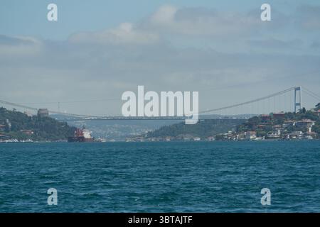 Un ponte affollato attraversa lo stretto del Bosforo a Istanbul, collegando Asia ed Europa, mentre le navi navigano nell'acqua sottostante. Foto Stock