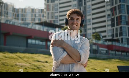 Bel caucasico uomo cuffie auricolari tecnologia dispositivo gadget ascoltare musica suono uomo uomo uomo d'affari città all'aperto studente playlist Foto Stock