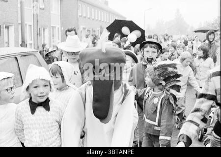 Festeggiamenti Heemskerk Driehuis IJmuiden Wijk aan Zee Queen's Day, Whizgle News, Dutch Desk, Paesi Bassi, 1950 - 2000 il 30-04-1974. Questi argomenti sono mostrati nell'immagine. La scena cattura una vivace parata piena di un gruppo diversificato di persone, molte delle quali sono vestite con vari costumi. Tra questi c'è una persona in un sorprendente costume cartoni animati con un naso grande, bulbo, simile a un becco e un design giocoso. Questa figura si distingue in prima linea, attirando l'attenzione con il suo aspetto eccentrico. Intorno a questo personaggio c'è una miscela di bambini e adulti, che sfoggia una varietà di abiti. Quindi Foto Stock