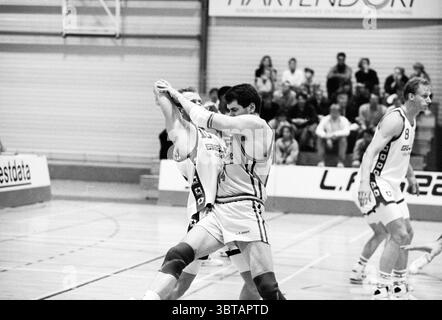 Akrides week Haarlem Paesi Bassi, Whizgle News, Dutch Desk, Paesi Bassi, 1950 - 2000 il 07-04-1992. Questi argomenti vengono visualizzati nell'immagine. In un ambiente sportivo indoor dinamico, due atleti sono impegnati in un'intensa lotta su un campo di legno, indicativo di una partita di basket. La scena viene catturata in una tavolozza monocromatica che presenta varie sfumature di grigio che conferiscono al momento una qualità senza tempo. I giocatori, indossando uniformi abbinate, sono raffigurati in un abbraccio ravvicinato, mostrando la loro determinazione e il loro sforzo. Un atleta è leggermente più alto, con un'espressione mirata, impegnato in un defensi Foto Stock