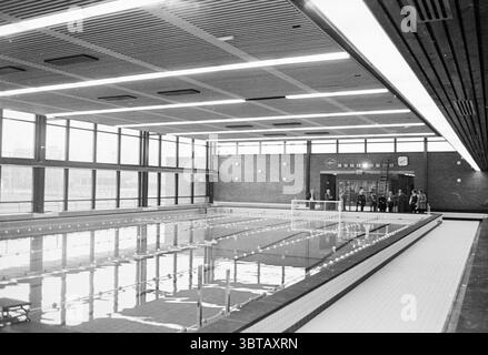 Piscina interna "De Planet" Haarlem Planetenlaan The Netherlands, Whizgle News, Dutch Desk, Paesi Bassi, 1950 - 2000 il 12-1971. Questi sono gli elementi dell'immagine. La scena raffigura una piscina interna, caratterizzata dalla sua architettura spaziosa e moderna. Le grandi finestre si estendono su un lato, consentendo un'ampia luce naturale ad inondare l'area, creando un'atmosfera luminosa e ariosa. La piscina stessa è piena di acqua scintillante, che riflette l'illuminazione dall'alto e l'ambiente circostante. Le pareti sono costruite con mattoni lisci e marroni, che offrono un caldo contrasto con il Foto Stock