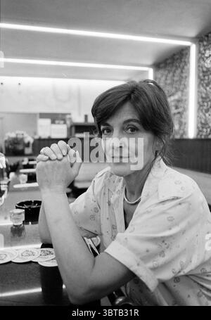Sig.ra Jeltes Badhoevedorp, Whizgle News, Dutch Desk, Paesi Bassi, 1950 - 2000 il 14-07-1992. L'immagine include questi argomenti. In un ambiente intimo e accogliente, una donna siede in un bar con le mani strette con attenzione davanti a lei. La barra presenta una superficie liscia che riflette la luce ambientale, creando un senso di calore. Ha un'espressione gentile che suggerisce la contemplazione, il suo sguardo si dirige leggermente verso il lato, trasmettendo un momento di introspezione. I capelli della donna sono modellati delicatamente, incorniciando il suo viso, e indossa una blusa di colore chiaro con sottili motivi floreali che forniscono una gastronomia Foto Stock
