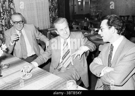 Reception Mr. Vos HD Haarlems Dagblad ecc. e ricevimenti IJmuider Courant e Koeri, Whizgle News, Dutch Desk, Paesi Bassi, 1950 - 2000 al 02-02-1981. Questi argomenti vengono visualizzati nell'immagine. La scena cattura tre uomini seduti intorno a un tavolo, impegnati in una conversazione. L'atmosfera è rilassata ma intellettualmente stimolante, suggerendo un incontro di amici o colleghi. Il tavolo e' adornato con una superficie testurizzata che presenta una tovaglia di colore chiaro che contrasta con le sfumature piu' scure dei mobili in legno intorno ad esso. Ogni uomo è vestito con abiti taglienti e sartoriali, che donano un'aria di Foto Stock
