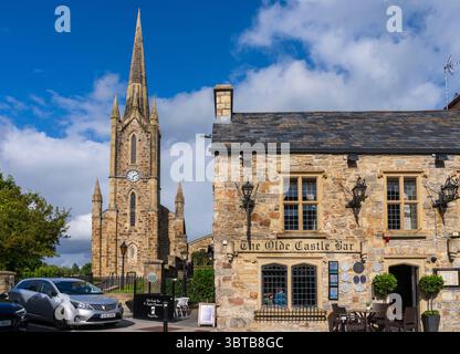 Donegal Town Church of Ireland con torre dell'orologio e guglia, accanto all'Olde Castle Bar and Restaurant, nella città di Donegal, Contea di Donegal, Irlanda. Foto Stock