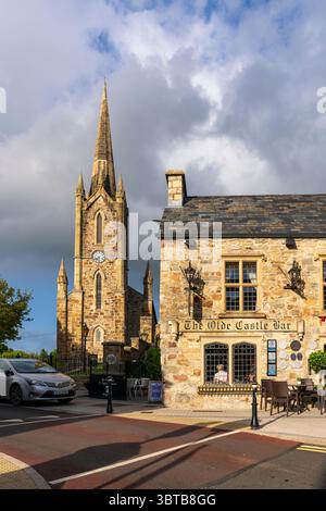 Donegal Town Church of Ireland con guglie e torre dell'orologio accanto all'Olde Castle Bar and Restaurant, un punto di riferimento molto conosciuto nella città di Donegal, Irlanda. Foto Stock