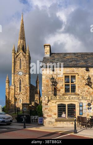 Donegal Town Church of Ireland con guglie e torre dell'orologio accanto all'Olde Castle Bar and Restaurant, un punto di riferimento molto conosciuto nella città di Donegal, Irlanda. Foto Stock