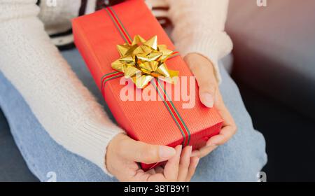 Donna anziana che celebra il Natale con un dono in mano, concetto di gioia per le vacanze. Incroci selettivi. Foto Stock