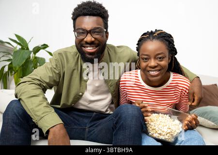 Giovane coppia che mangia popcorn e guarda la tv a casa Foto Stock