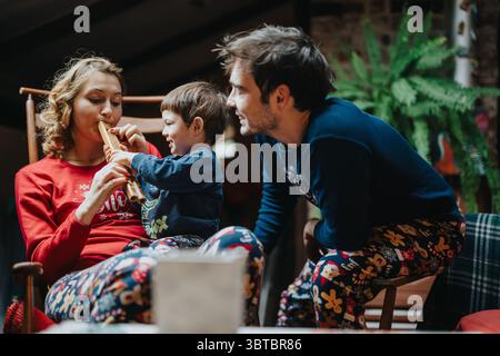 Le famiglie si godono momenti di qualità insieme nei pigiama festivi a casa Foto Stock
