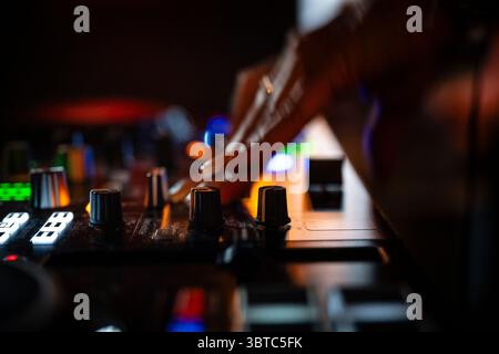 Primo piano di un DJ che mescola la musica con le dita e le mani. le dita toccano manopole, manopole e interruttori e riproduce e mixa musica. Foto Stock