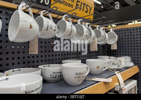 Poznan, Polonia - 30 giugno 2025: Una vista ravvicinata di tazze e ciotole in ceramica bianca ordinate con disegni concettuali, esposte in un vivace negozio al dettaglio Foto Stock
