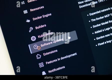 Poznan, Polonia - 30 giugno 2025: Primo piano di un cursore del mouse che indica l'impostazione "aggiornamenti software" all'interno di un'applicazione contemporanea in modalità oscura Foto Stock