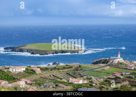 Faro di Ponta do topo e vista sull'isolotto da Sao Jorge Azzorre Portogallo. Paesaggio dell'isola atlantica, villaggio costiero, scogliere spettacolari, Portu tradizionale Foto Stock