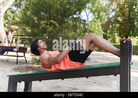 Sportivo concentrato che fa esercizi addominali all'aperto, promuovendo uno stile di vita sano e il fitness in ambiente urbano Foto Stock