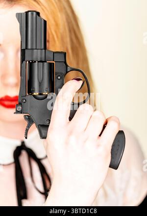 Una donna ha in mano una pistola, con il dito sul grilletto. Foto Stock