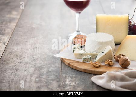 Tagliere di formaggi diversi con noci, fichi e uva su tavola di legno Foto Stock