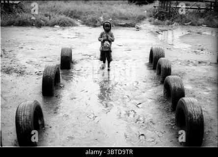 14 maggio 2014, Pietermaritzburg, KwaZulu Natal, Sud Africa: Un bambino fuori dal vecchio centro sportivo ai margini dell'insediamento informale Jika Joe...Jika Joe è un insediamento informale che si trova a cavallo di entrambe le sponde del fiume Dorpspruit nel centro di Pietermaritzburg, la capitale della provincia di KwaZulu Natal in Sud Africa. La sua massa è fatta di fango, frammenti di legno e cartone, i tetti di Jika Joe sono in lamiera, pezzi di pannelli rigidi e teloni venduti spazzati via dai camion di passaggio su una vicina autostrada. ..la vista di queste case autocostruite su tratti aperti di terra sudafricana non è goin Foto Stock