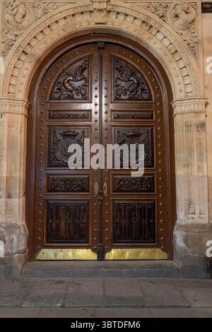 Una porta di legno splendidamente realizzata sorge in un edificio storico a Zamora. La porta presenta intricate incisioni con uno stemma che riflette l'ar Foto Stock
