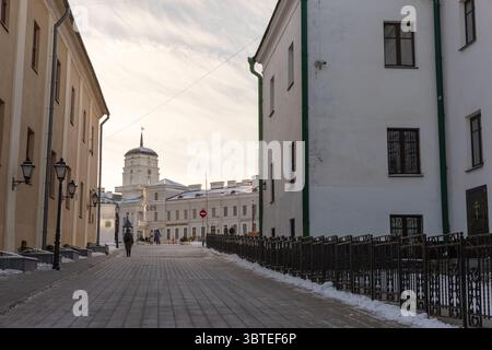 Minsk, Bielorussia - 7 gennaio 2024: Una tranquilla scena invernale caratterizzata da una strada acciottolata che conduce allo storico municipio di Minsk con surro coperto di neve Foto Stock