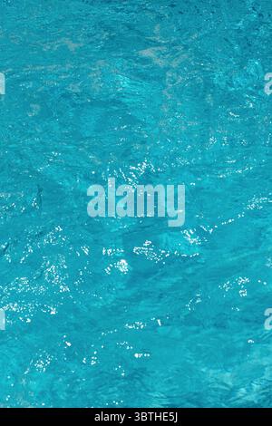 Acqua blu della piscina con increspature e riflessi di luce solare. Foto Stock