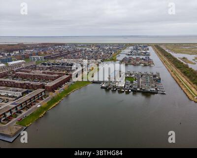 Vista aerea delle case e delle boatouses moderne fiancheggiano le acque tranquille, riflettendo il cielo mite di Almere, Flevoland, Paesi Bassi. Foto Stock
