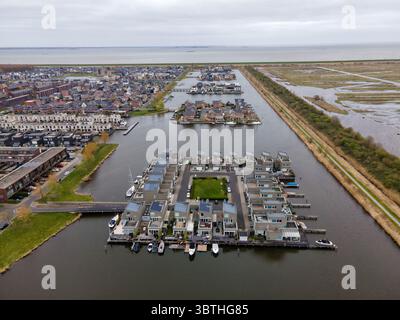 Vista aerea delle moderne case galleggianti con pannelli solari e barche, annidate nelle acque tranquille vicino alla costa di Almere, Flevoland, Paesi Bassi. Foto Stock