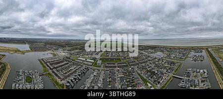 Vista aerea delle case con tetti scuri e piccoli canali che riflettono il cielo nuvoloso della zona, Almere, Flevoland, Paesi Bassi. Foto Stock