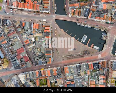 Vista aerea delle barche attraccate nel porticciolo, circondate da edifici dal tetto rosso e da una piazza centrale, che cattura l'essenza del vivace lungomare della città, Almere, Flevoland, Paesi Bassi. Foto Stock