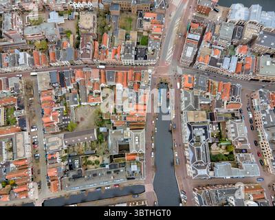 La vista aerea dei tetti e dei canali si intreccia, riflettendo il cielo, mentre auto e barche navigano lungo i corsi d'acqua tra gli edifici di Almere, Flevoland, Paesi Bassi. Foto Stock