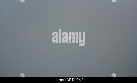 Una vista serena con una persona solitaria su una zattera che naviga pacificamente sulle acque calme, offrendo un senso di solitudine. Foto Stock