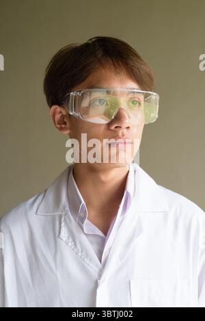 Giovane scienziato asiatico studente ricercatore che indossa camice da laboratorio Foto Stock