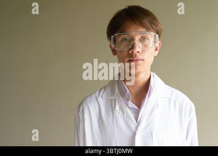 Giovane scienziato asiatico studente ricercatore che indossa camice da laboratorio Foto Stock