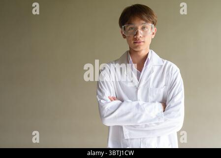 Giovane scienziato asiatico studente ricercatore che indossa camice da laboratorio Foto Stock