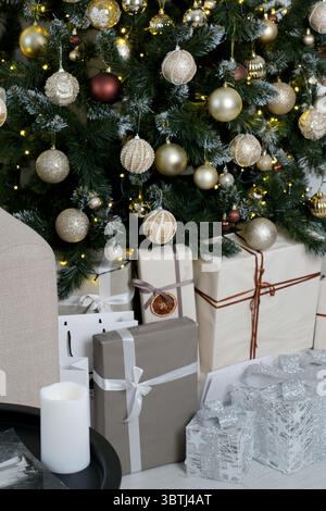 Un delizioso albero di Natale si erge tra regali e luci scintillanti. Foto Stock