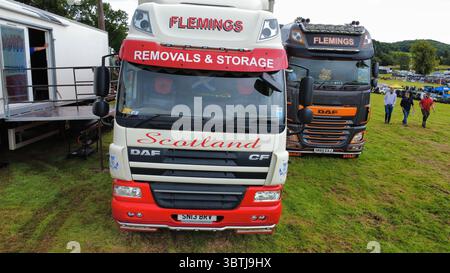 Vista aerea di una fila di veicoli industriali lucidati, compresi i modelli Scania, Volvo e DAF, parcheggiati su un campo erboso durante una fiera dei veicoli in Scozia Foto Stock