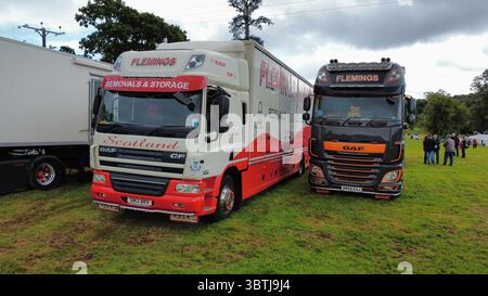 Vista aerea di una fila di veicoli industriali lucidati, compresi i modelli Scania, Volvo e DAF, parcheggiati su un campo erboso durante una fiera dei veicoli in Scozia Foto Stock