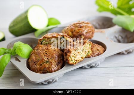 Muffin di zucchine vegetariane in una presentazione luminosa su un tavolo di legno chiaro. Foto Stock