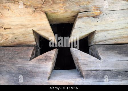 Sfondo testurizzato da vecchie pareti esterne in legno di una casa con una finestra tagliata a forma di croce Foto Stock
