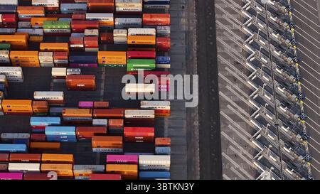 Long Beach, Stati Uniti - 07 aprile 2025: Veduta aerea di una moltitudine di container che creano un vivace arazzo di colori contro le linee geometriche e aspre dell'infrastruttura del porto. Foto Stock