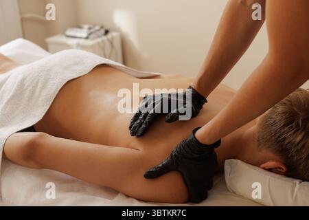 Specialista della riabilitazione che esegue un massaggio terapeutico per la cura della colonna vertebrale, la scoliosi e il dolore alla schiena in ambiente clinico Foto Stock