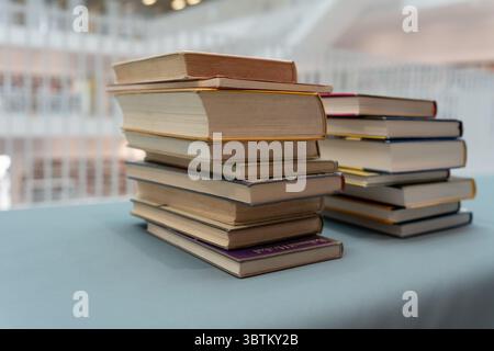 Ci sono molti libri sul tavolo. Una grande pila di libri viene raccolta in un unico posto. Una pila di libri che giace sul tavolo. Foto Stock