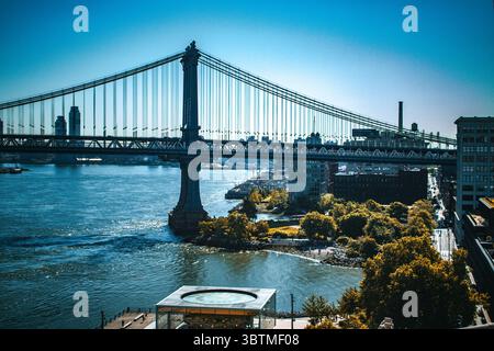 La vista del ponte di Brooklyn dal lungomare, con splendidi cieli blu. Ponte sospeso in acciaio cablato da Manhattan a Brooklyn, New York. Foto Stock