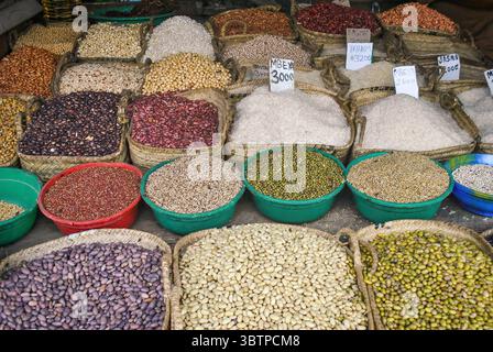 Varietà di cereali, fagioli e riso esposti in cesti e ciotole di plastica in un mercato all'aperto. Foto Stock