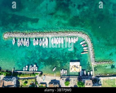 Vista aerea dall'alto verso il basso delle barche a vela bianche ancorate a mezzaluna in un porto turchese a Yvoire France Foto Stock
