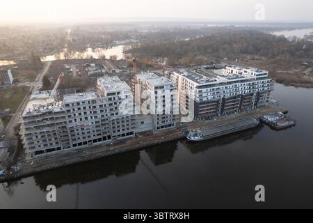 Vista aerea di un'area immobiliare su larga scala su una riva del fiume. Il sito mostra moderni condomini a più piani in varie fasi di Foto Stock