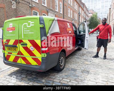 Vista posteriore del furgone elettrico a emissioni zero Royal mail, mentre Happy Delivery driver apre lo sportello della cabina per la consegna successiva nel centro di Londra nel Regno Unito Foto Stock