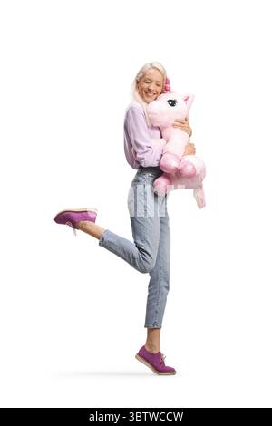 Donna felice che abbraccia un grande unicorno rosa isolato su sfondo bianco Foto Stock